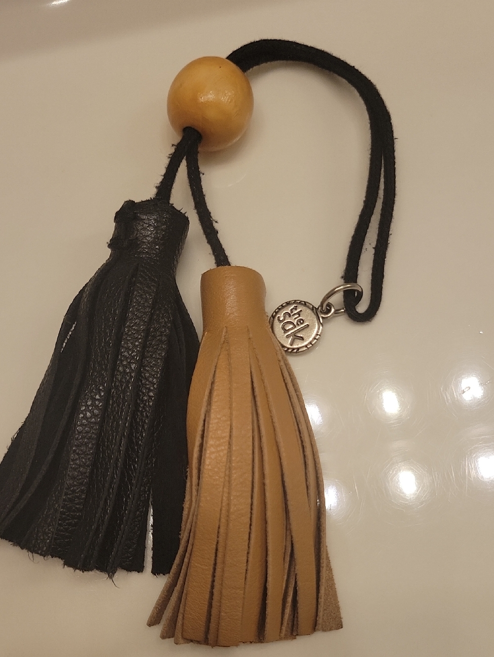 The Sak Leather Tassel Bag Charm in Black & Tan with a Wood Bead Accent